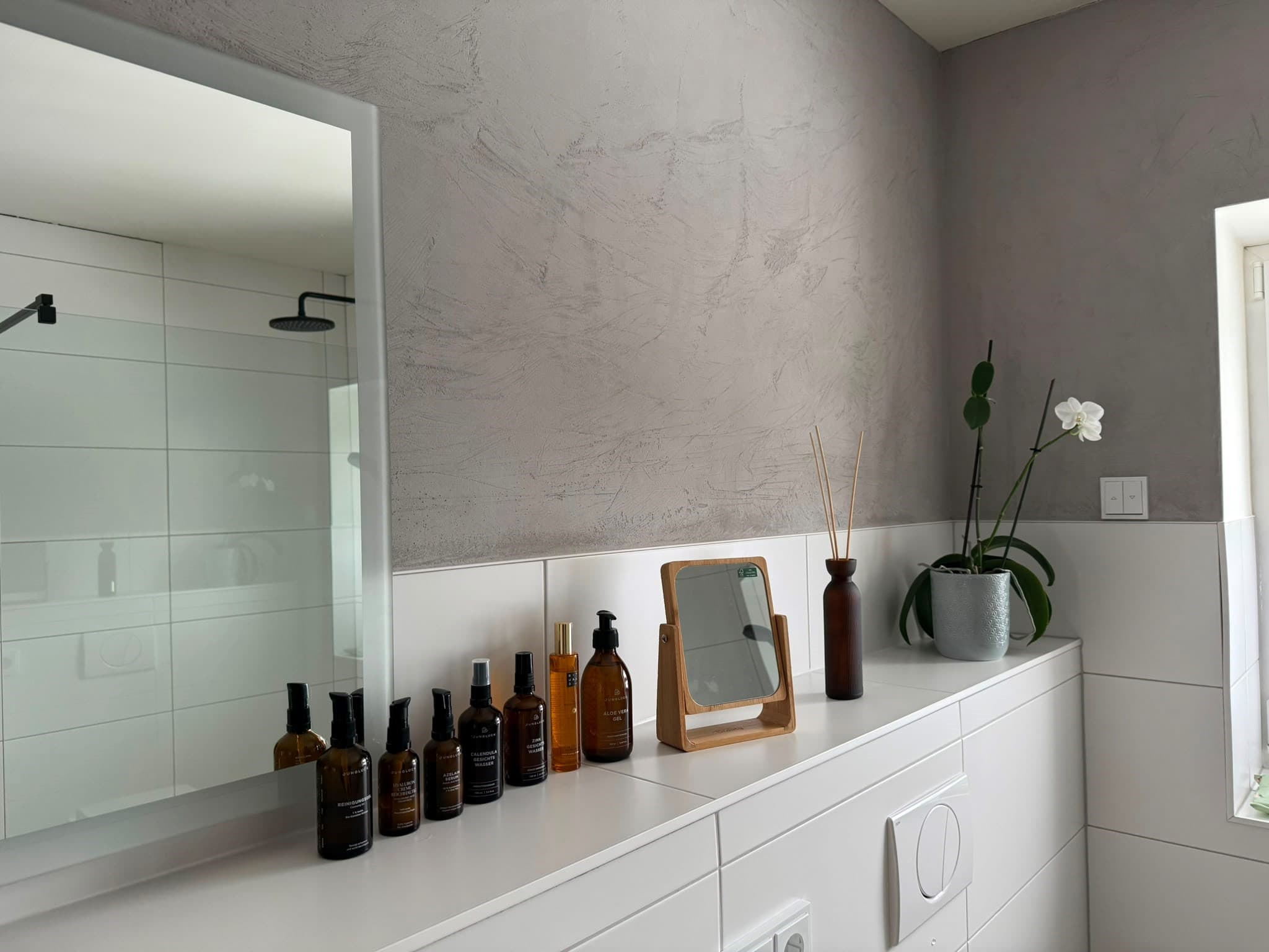 Elegantes Badezimmer mit Lehmputz-Wandgestaltung, Orchidee und Naturkosmetik